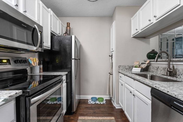 Galley kitchen with white cabinets, stainless steel appliances, and plenty of storage