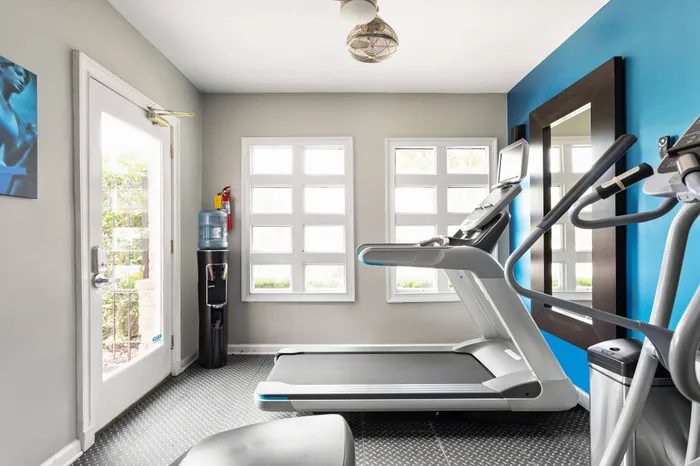 Cardio machines in apartment fitness center with large windows and water cooler