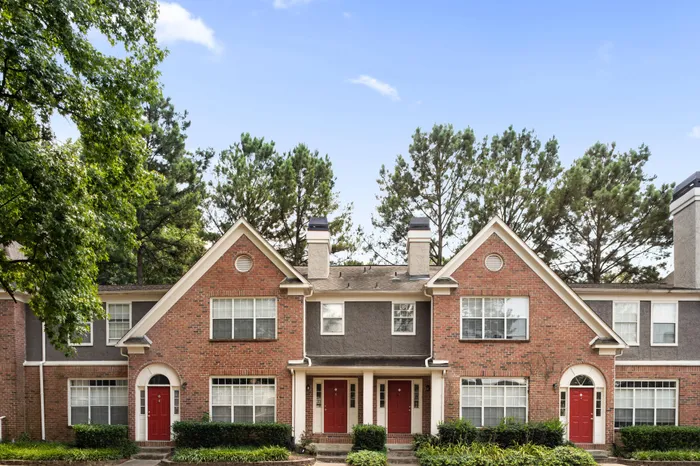 Exterior of Arbors River Oaks Apartment Homes, a brick building with red doors