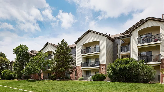 Charming apartment complex with spacious balconies, surrounded by lush greenery and a vibrant natural setting.