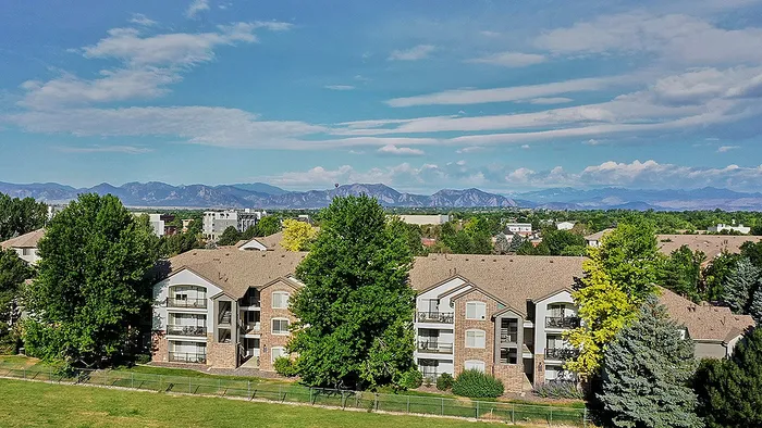 Charming apartment complex nestled amidst lush greenery with stunning mountain views in the distance.