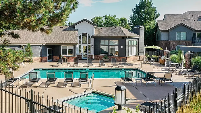 Inviting outdoor pool area with modern lounge chairs and lush greenery, ideal for relaxation and leisure.