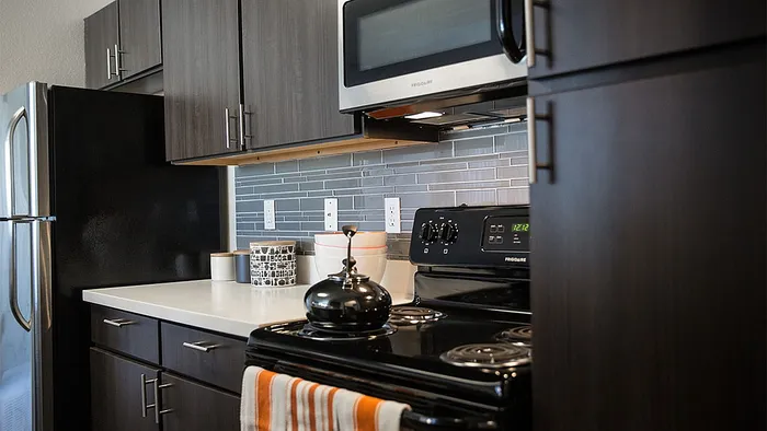 Contemporary kitchen with sleek dark cabinetry, modern appliances, and stylish backsplash.
