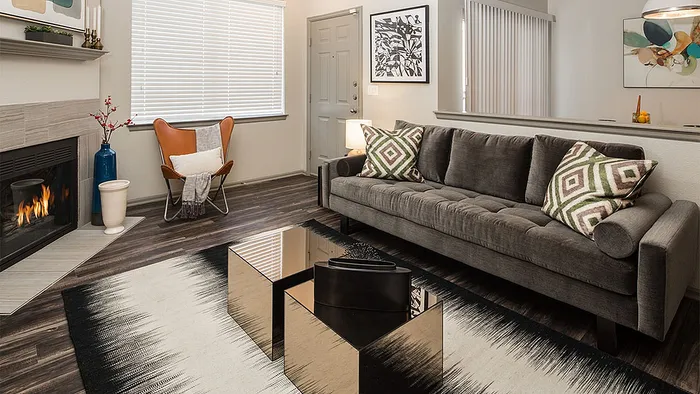 Contemporary living room with a stylish gray sofa, chic geometric pillows, and a cozy fireplace. Features modern decor, a sleek coffee table, and warm lighting for a welcoming atmosphere.