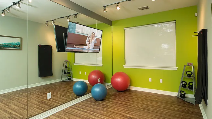 Modern home gym with vibrant green walls, mirrored wall, exercise balls, and kettlebell rack, perfect for at-home workouts.
