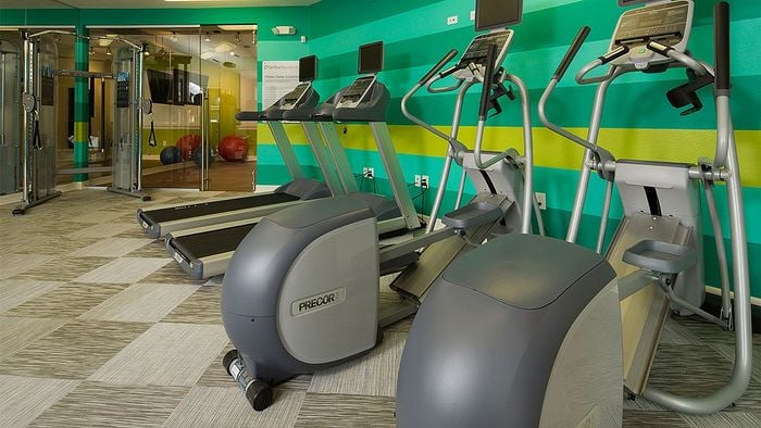 Modern apartment gym equipped with state-of-the-art cardio machines, vibrant decor, and a spacious workout area.