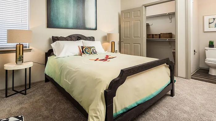 Inviting bedroom with modern decor, cozy bedding, and an elegant walk-in closet, exuding comfort and style.