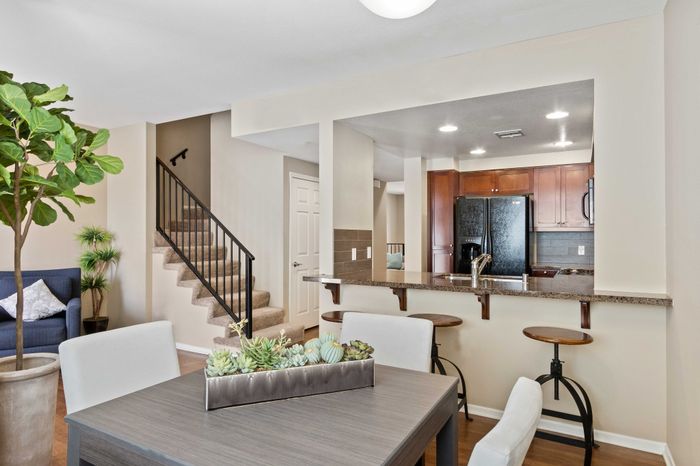 Chic open-concept apartment with elegant staircase, cozy living area, and modern kitchen with breakfast bar seating.