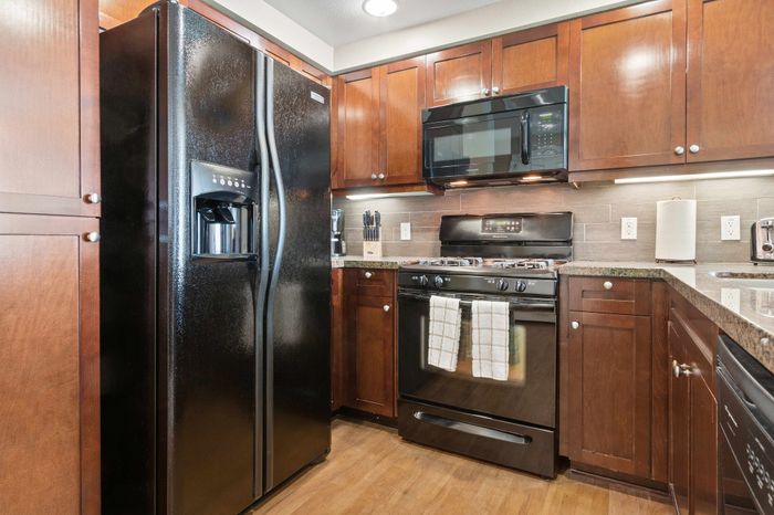 Modern kitchen featuring sleek black appliances, elegant wooden cabinetry, and granite countertops that enhance the contemporary ambiance.