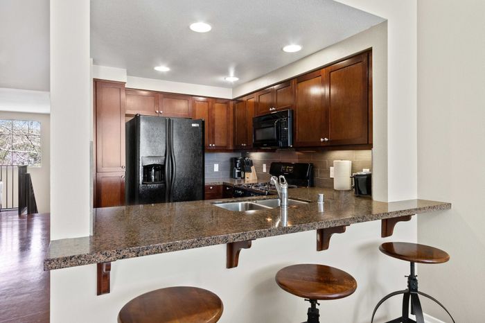 Modern kitchen with sleek granite countertops, stainless steel appliances, and rich wooden cabinets, perfect for culinary enthusiasts.