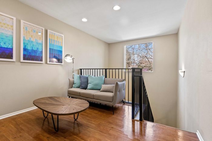 Bright and inviting modern loft area with cozy sofa, stylish artwork, and natural light flowing through large window.