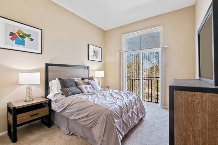 Inviting bedroom with modern decor, plush bedding, and large window offering a scenic view.