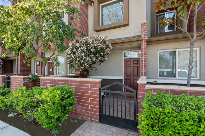 Charming townhouse entrance with lush greenery, brick facade, and welcoming front door.