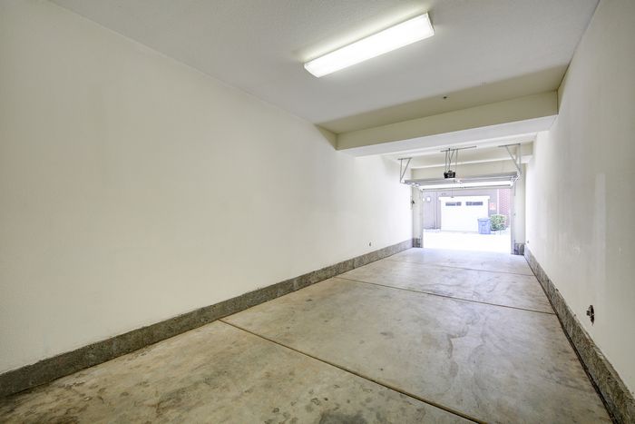 Spacious and clean indoor garage with sleek concrete flooring and bright lighting, perfect for secure parking and storage.