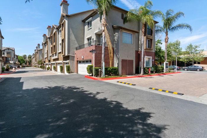 Charming residential complex with modern architecture, featuring lush palm trees and well-maintained surroundings under a clear blue sky.