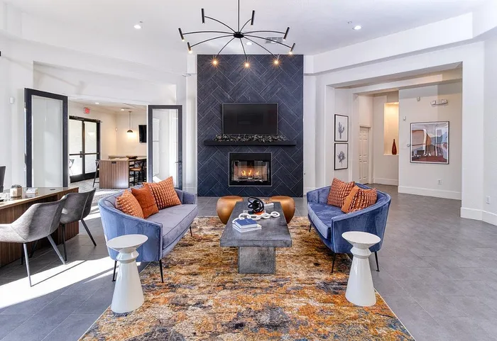 Elegant living room with plush blue sofas, modern fireplace, and chic chandelier, perfect for a cozy and stylish ambiance.