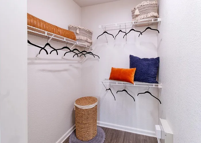 Spacious walk-in closet with sleek shelving, stylish hangers, and cozy decorative pillows, offering ample storage and modern elegance.
