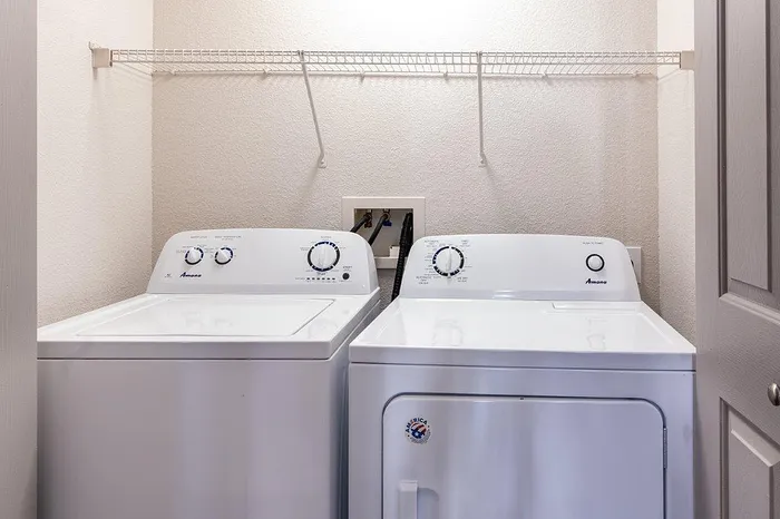 Modern laundry room featuring a sleek washer and dryer set with convenient shelving space.