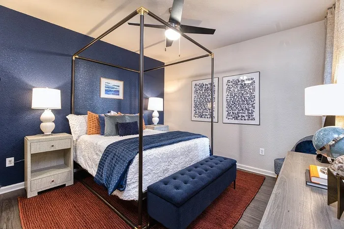 Elegant bedroom with a luxurious canopy bed, deep blue accents, and stylish modern decor, offering a cozy and inviting atmosphere.