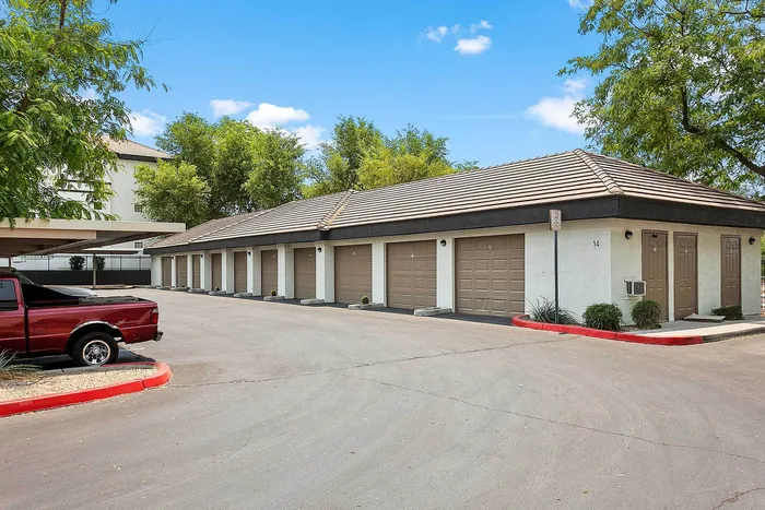 Inviting apartment complex with a row of stylish garages and crisp landscaping under a bright blue sky.