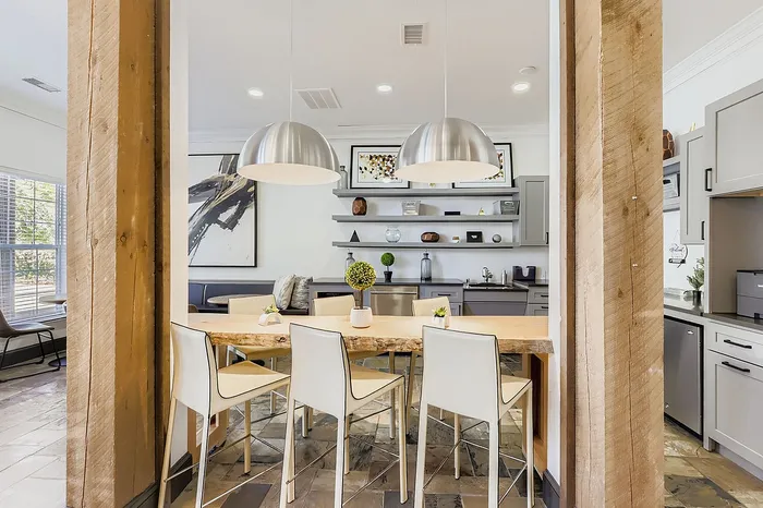 Modern kitchen with chic lighting, sleek appliances, and a rustic table that invites warmth and style.