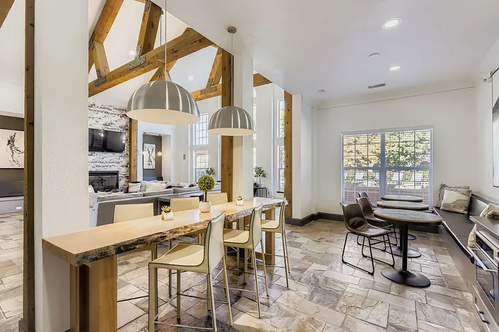 Elegant open living area featuring vaulted ceilings, modern dining space, and stylish lounge in a bright setting.