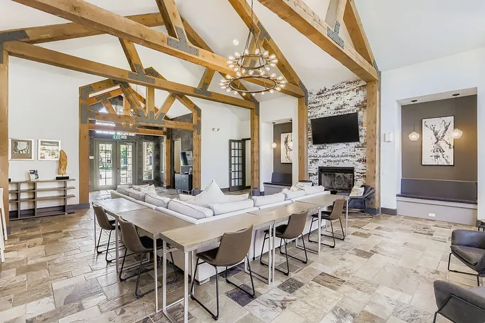 Elegant living room with rustic wood beams, modern chandelier, cozy fireplace, and spacious seating area.