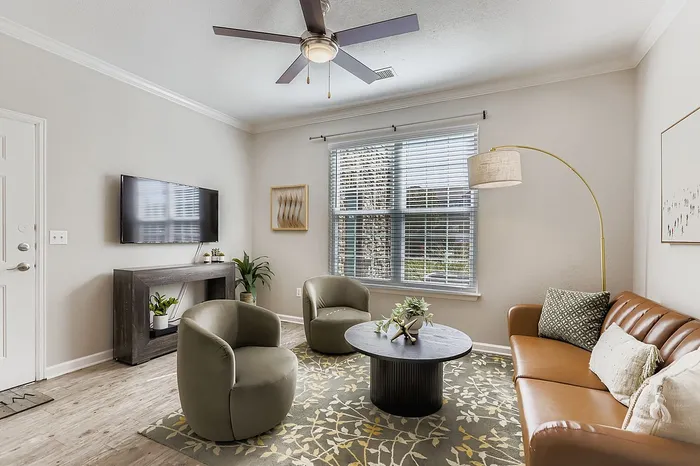Inviting living room with modern leather sofa, stylish armchairs, and elegant decor in a sunlit space.