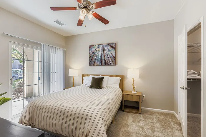 Cozy bedroom with elegant decor, featuring a plush bed, ambient lighting, and sliding glass doors leading to an inviting outdoor space.