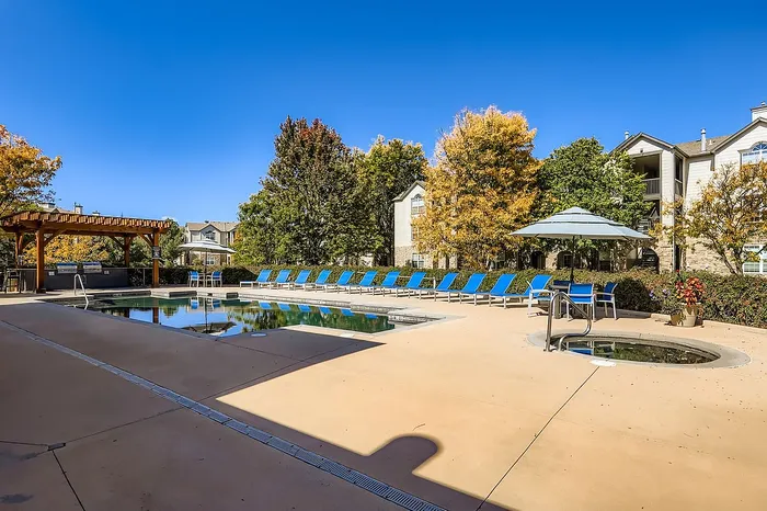 Inviting apartment complex with a sparkling outdoor pool, stylish sun loungers, and lush landscaping, perfect for relaxing and socializing.