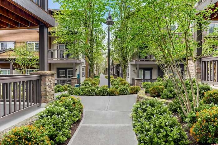 Charming apartment exterior with lush greenery, vibrant landscaping, and inviting walkways leading to elegant multi-story buildings.
