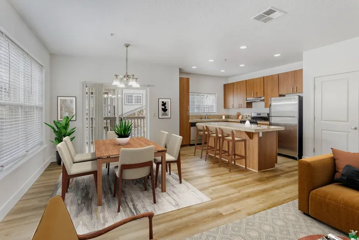 Bright and inviting open-concept dining and kitchen area with sleek wood cabinets, modern appliances, and elegant decor.