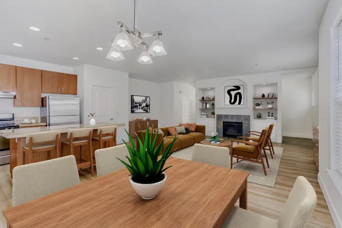 Elegant open-concept living and dining area featuring modern wood cabinetry, cozy fireplace, and sleek stainless steel appliances for a stylish home experience.