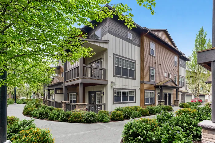 Charming multi-story apartment building nestled in lush greenery, featuring modern architectural design and spacious balconies.