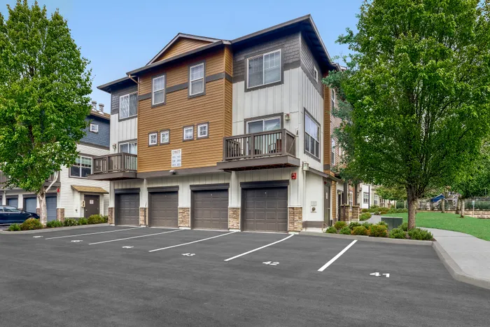 Charming townhouse with rustic wooden facade, three garages, and lush green surroundings.