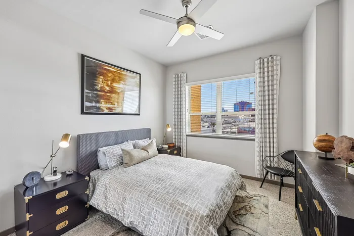 Contemporary bedroom with large window view, featuring a stylish bed, elegant artwork, and modern furniture accents.