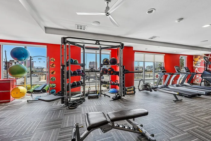 Modern fitness center with vibrant red accents, featuring top-notch gym equipment, treadmills, free weights, and a city view for an inspiring workout experience.