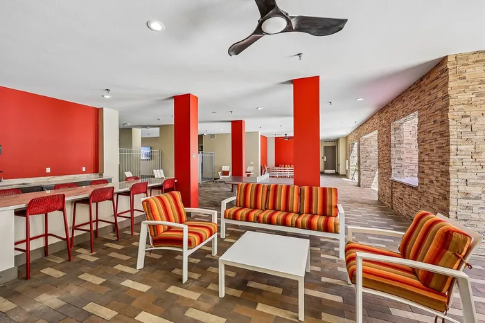 Vibrant communal lounge area with modern seating, colorful decor, and stylish stone walls, perfect for social gatherings.