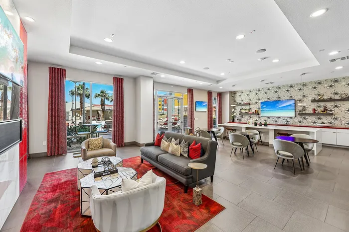 Chic and modern lounge area featuring stylish furniture, vibrant red decor, and large windows with poolside views.