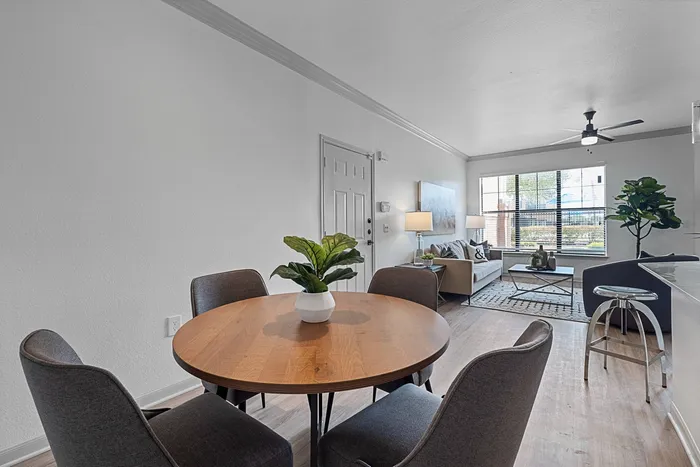 Model dining room with table, chairs, and décor with the living room in the background.