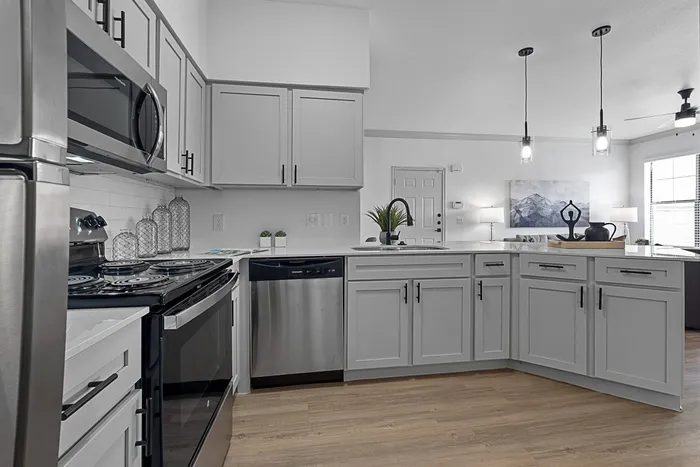 Kitchen with stainless appliances, white cabinets, white countertops and wood style flooring