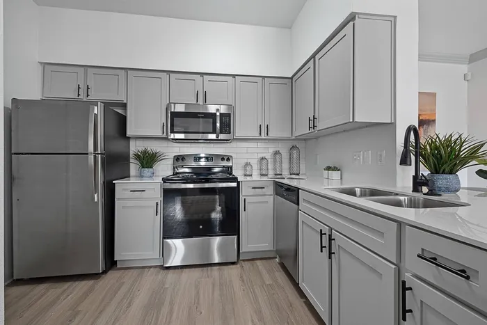 Kitchen with stainless appliances, white cabinets, white countertops and wood style flooring