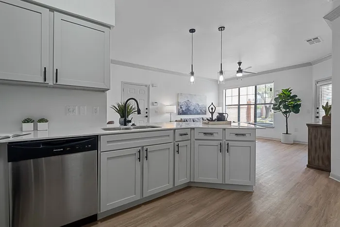 Kitchen with stainless appliances, white cabinets, white countertops and wood style flooring