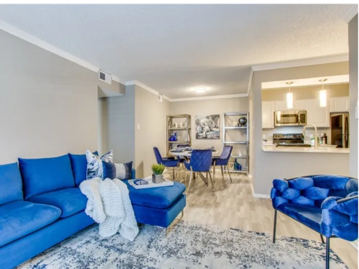 Vinyl floor living space with blue couch, wall art, kitchen bar, and bar