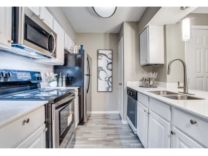 Modern kitchen featuring vinyl flooring, stainless-steel appliances, and a white quartz countertop