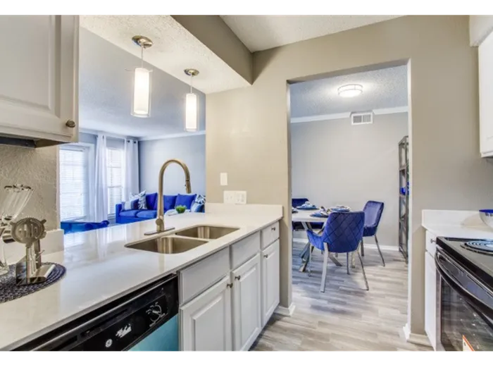 Kitchen with vinyl floors, stainless-steel appliances, white quartz countertop, and pendant lighting