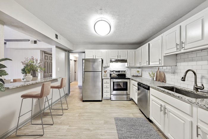 Vinyl floors, stainless-steel appliances, white quartz countertop, and pendant lighting