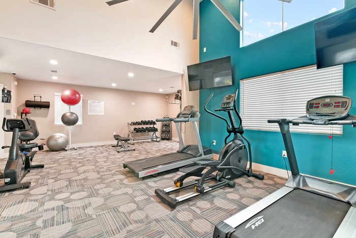Fitness center with cardio equipment, TV, and ceiling fan
