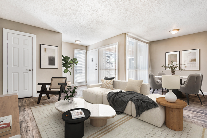 Living space with hard wood style flooring, white couch with through pillows, beige rug, round dining table, gray chairs