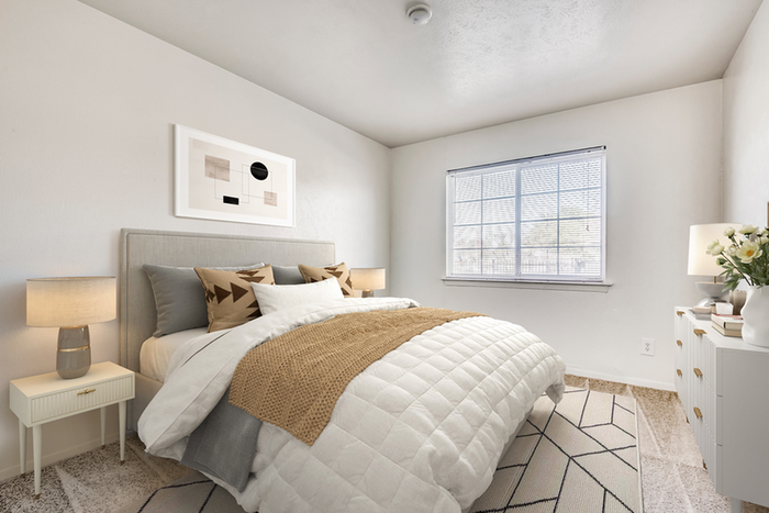 Bedroom with queen size bed with throw pillows, white dresser, rug and hard wood style flooring